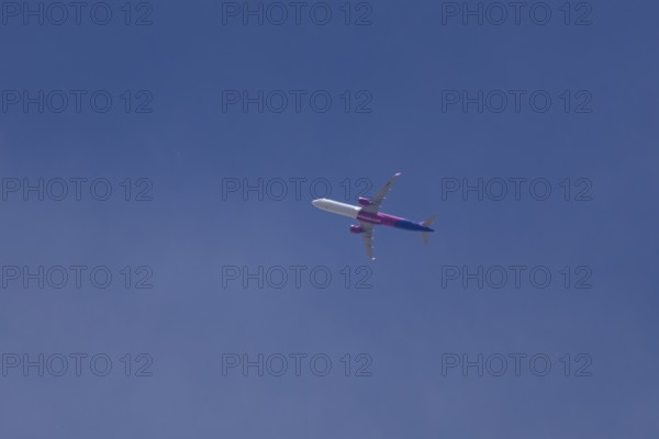 Airbus A321 jet aircraft of Wizz Air airlines in flight in a blue sky, England, United Kingdom