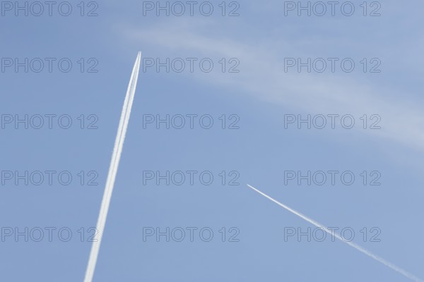 Two jet passenger aircraft with vapour trails or contrails flying in a blue sky, England, United Kingdom