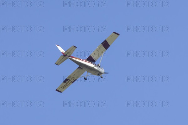 Reims Cessna F172M Skyhawk light aircraft flying in a blue sky, England, United Kingdom