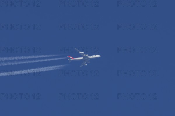 Boeing 747 jumbo jet cargo aircraft of Cargolux airlines with a vapour trail or contrail flying in a blue sky, England, United Kingdom