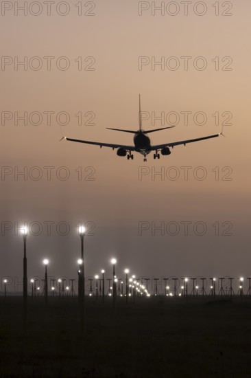 Boeing 737 jet passenger aircraft of Ryanair airlines landing over runway lights at sunset, London Stansted airport, Essex, England, United Kingdom