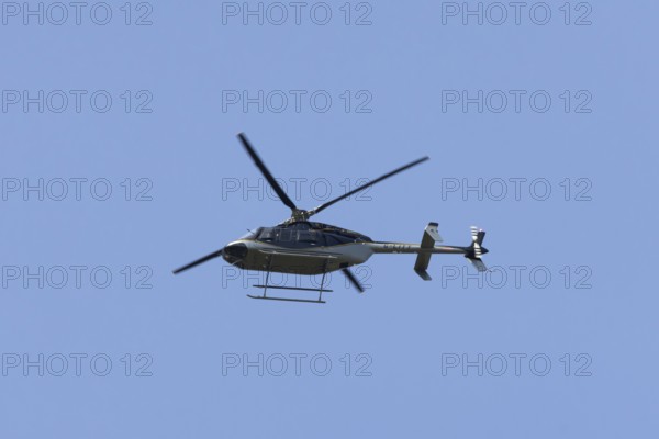 Bell 407GXP jet ranger helicopter flying in a blue sky, England, United Kingdom