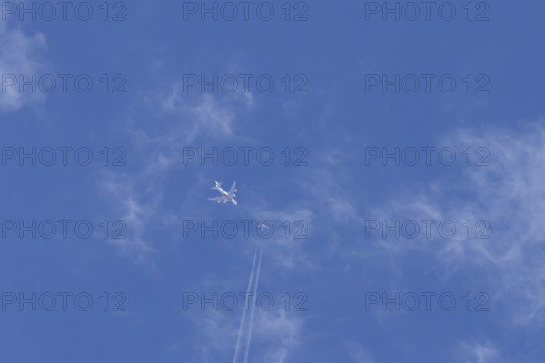 Two airliners Airbus A380 jet passenger aircraft of Emirates airlines and a Boeing 737 of Norweign Air flying in a blue sky, England, United Kingdom