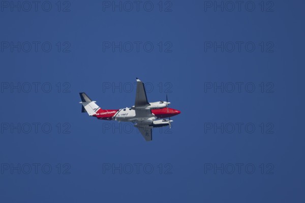 Beech King Air 350 light aircraft of the UK HM Coastguard flying in a blue sky, England, United Kingdom
