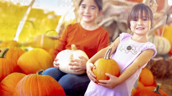 Two girls holding their pumpkins at A pumpkin patch on a fall day