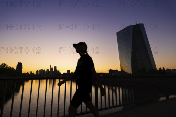 The sun sets behind the European Central Bank (ECB) and the Frankfurt banking skyline, Frankfurt am Main, Hesse, Germany