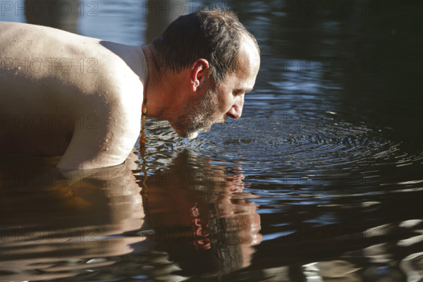 Man in the water during body care while travelling, Müritz National Park, Mecklenburg-Western Pomerania, Germany