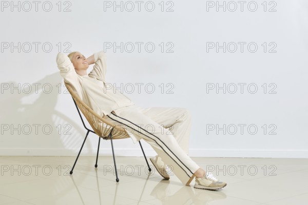 Relaxing in a modern chair, a woman enjoys a quiet moment in a minimalist indoor space