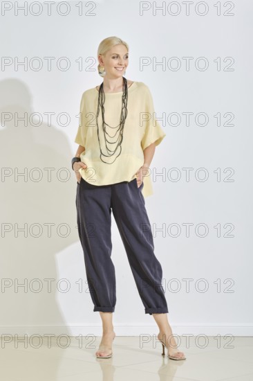 Model stands confidently in a stylish ensemble consisting of a light-colored top and dark trousers