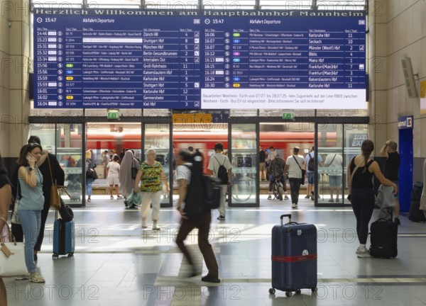 Mannheim main station, interior view with people and display board. Mannheim, Baden-Württemberg, Germany