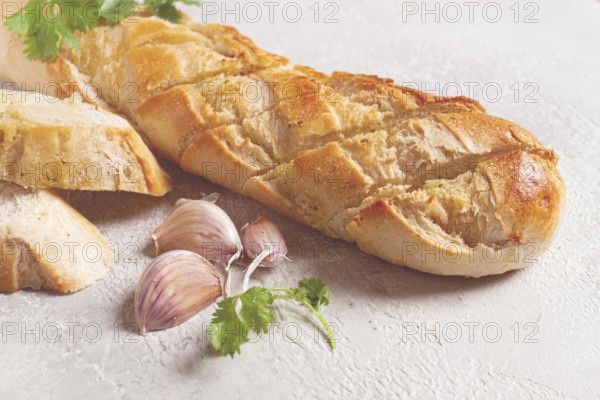 Garlic bread, baguette with garlic butter and herbs, on a light table, top view