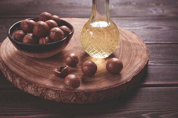 Bottle of macadamia oil, on a wooden board, with macadamia nuts, wooden background, selective focus, no people