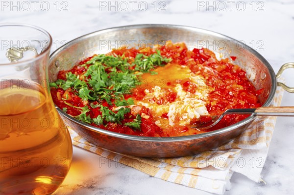 Traditional Turkish dish, scrambled eggs with tomatoes, Menemen, with herbs, in a frying pan, close-up, no people