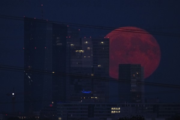 The full moon passes over the Frankfurt banking skyline, Frankfurt am Main, Hesse, Germany