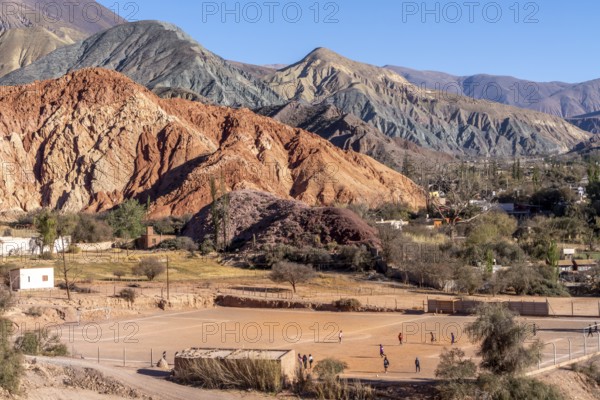 Young people playing football, with coloured hills in the background, erosion, Purmamarca, Jujuy, Argentina