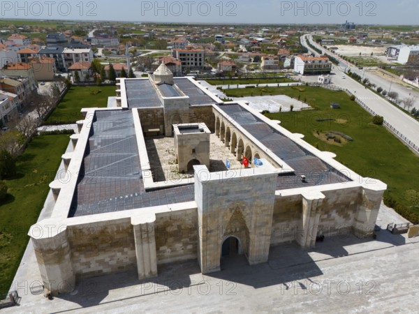 Historic stone caravanserai with courtyard and Tor tor, surrounded by modern urban landscape, aerial view, Sultanhani caravanserai, Sultanhani, Aksaray province, historic Silk Road, Turkey