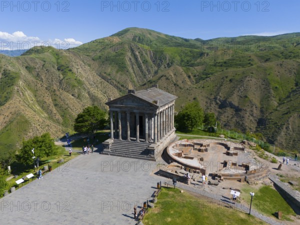 Ancient temple in a green mountain landscape with ruins and clear sky, aerial view, Temple of Garni, Garni, Kotayk province, Armenia