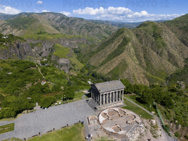 Aerial view of an ancient temple in the middle of a green mountain landscape under a cloudy sky, aerial view, Temple of Garni, Garni, Kotayk province, Armenia