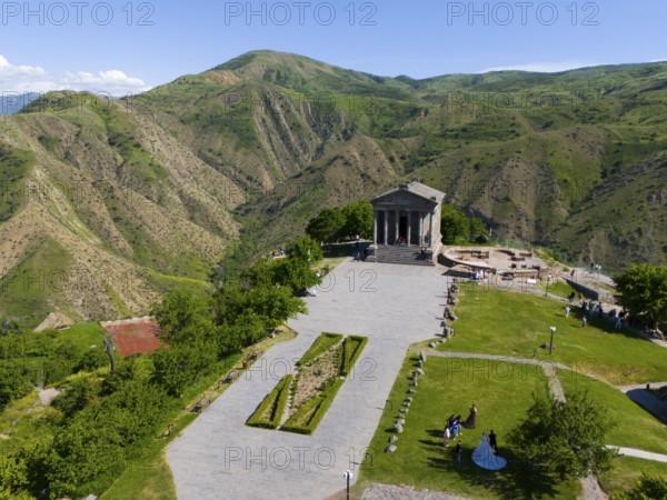 Ancient temple in front of a green mountain backdrop, under a blue sky in a sunny landscape, aerial view, Temple of Garni, Garni, Kotayk province, Armenia