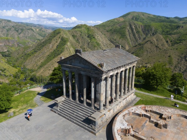 Ancient temple with columns in a green mountain landscape under a blue sky with clouds, aerial view, Temple of Garni, Garni, Kotayk province, Armenia