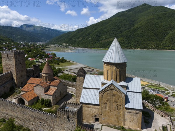 Medieval fortress and church with mountains and river in the background, under blue sky with clouds, aerial view, Ananuri castle, Zhinvali reservoir, Shinvali, Jinvali or Shinvali, Mtskheta-Mtianeti region, Georgian Military Road, Georgia