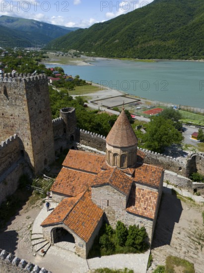 Red tiled roof of a medieval fortress church with castle walls and green lake panorama, aerial view, Ananuri Castle, Zhinvali reservoir, Shinvali, Jinvali or Shinvali, Mtskheta-Mtianeti region, Georgian Military Road, Georgia