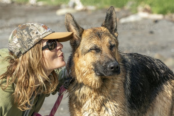 Woman blowing in her German Shepherd's ear, the dog is annoyed, Gaspesie Region, Province of Quebec, Canada, North America