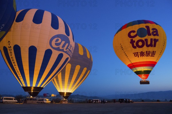 Glowing hot air balloons against a deep blue morning sky create a peaceful atmosphere on a plateau, Göreme National Park, Göreme Tarihî Millî Parki, Nevsehir Province, Nevsehir, Cappadocia, Cappadocia, Cappadocia, Cappadocia, Central Anatolia, Turkey