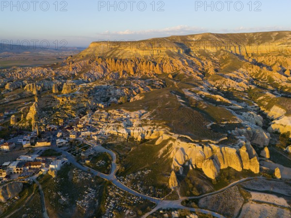 A picturesque landscape with rock formations and a small village in warm sunset light, aerial view, Göreme National Park, Göreme Tarihî Millî Parki, Nevsehir Province, Nevsehir, Cappadocia, Cappadocia, Kapadokya, Cappadocia, Central Anatolia, Turkey