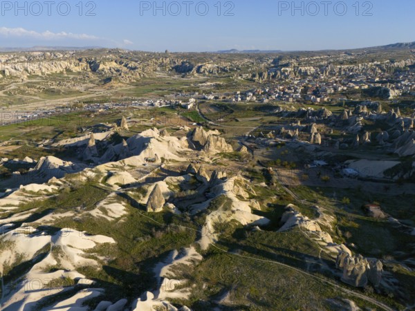Vast landscape with striking rock formations and a village under a blue sky, aerial view, Göreme National Park, Göreme Tarihî Millî Parki, Nevsehir Province, Nevsehir, Cappadocia, Cappadocia, Kapadokya, Cappadocia, Central Anatolia, Turkey