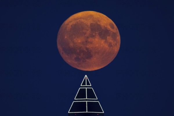 The full moon passes over the top of the Messeturm in Frankfurt am Main, Frankfurt am Main, Hesse, Germany