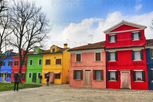 Strollers, typical street scene in winter, colourful facades of fishermen's houses in Burano, island in the lagoon of Venice, Italy