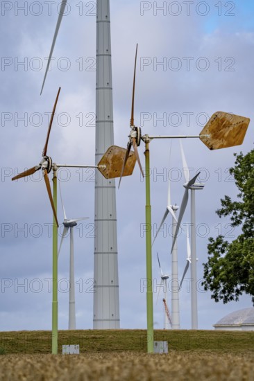 Mini wind turbines, from the Dutch company Ecoways EAZ wind turbine, produces up to 15 kW power and up to 45, 000 KW electricity per year, for self-consumption, intended primarily for farms, rotors made of wood, from forests in the Netherlands, easy to recycle, quick and easy to set up, for cheap power supply in the countryside, behind it large wind turbines of a wind farm near Eemshaven, Netherlands