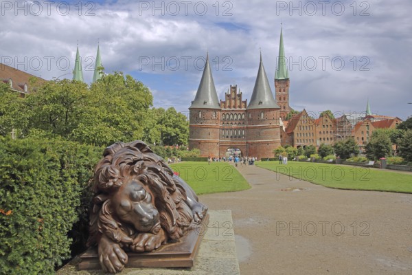 Sleeping lion figure at the historic Holstentor and St. Peter's church tower in Lübeck, Brick Gothic, Brick building, City gate, Landmark, Holstentorplatz, Old town, Lübeck, Schleswig-Holstein, Germany