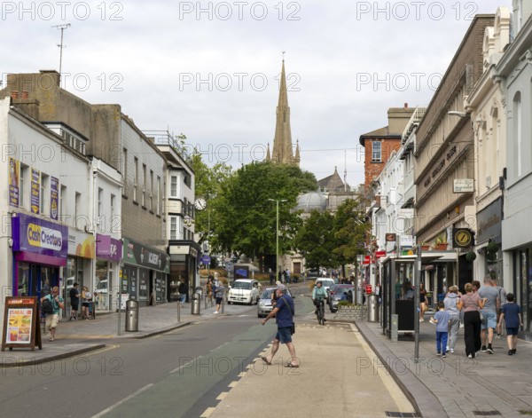 Shops in street of historic buildings, Union Street, Torquay, Devon, England, UK view to church spire