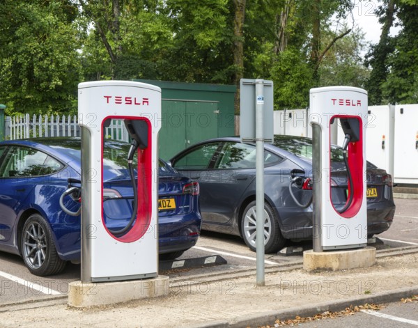 Tesla Supercharger station charging bays for electric vehicles at service station, M25 South Mimms services, Hertfordshire, England, UK