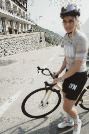 Young woman riding a racing bike on Lake Garda. Sunny weather and dolce vita