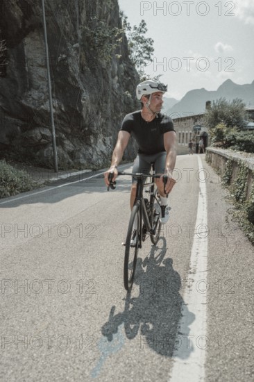 Young man riding a racing bike on Lake Garda. Sunny weather and dolce vita