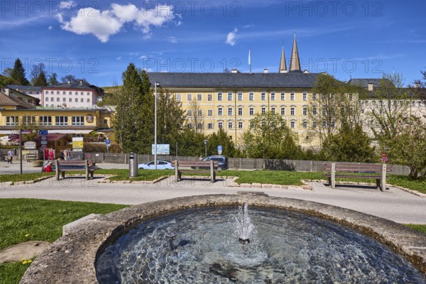 Royal Castle Berchtesgaden, Fischerbrunnen, master stonemason August Wolf, fountain, fountain made of stone, general architecture, trees, lawn, parking strip with vehicles, wooden fence, lantern, benches, blue sky, cumulus clouds, cirrostratus clouds, Am Fischerbichl, Bahnhofstraße, Berchtesgaden, Upper Bavaria, district Berchtesgadener Land, Bavaria, Germany