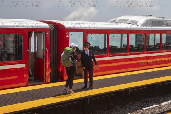 Colorado Springs, Colorado - A conductor talks with a passenger after the Manitou and Pikes Peak Railway has reached the 14, 115-foot summit of Pikes Peak