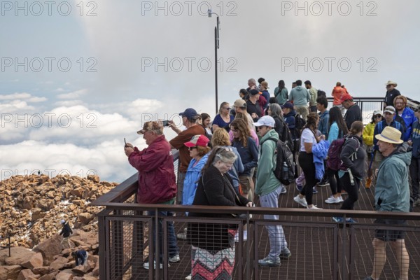Colorado Springs, Colorado - Tourists on a viewing platform on Pikes Peak, a 14, 115' mountain in Colorado's front range. Thousands of tourists visit, most by driving a steep road to the summit, or riding on a cog railway