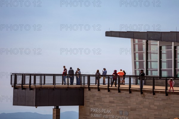Colorado Springs, Colorado - Tourists on the viewing platform at the Pikes Peak Summit Visitor Center. Pikes Peak is a 14, 115' mountain in Colorado's front range. Thousands of tourists visit, most by driving a steep road to the summit, or riding on a cog railway