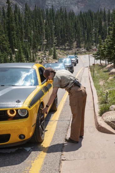 Colorado Springs, Colorado - A Pikes Peak ranger checks the temperature of brakes on a car descending 14, 115' Pikes Peak. If the brakes have become hotter than 300 degrees F, travelers must stop to let the brakes cool before continuing their descent