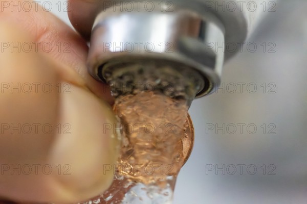 Symbolic image of a water cent: A cent piece under a running tap
