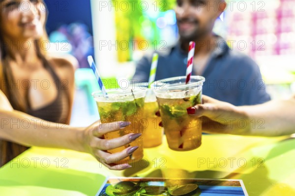 Friends enjoying refreshing mojito cocktails at a vibrant beach bar, celebrating summer with a toast