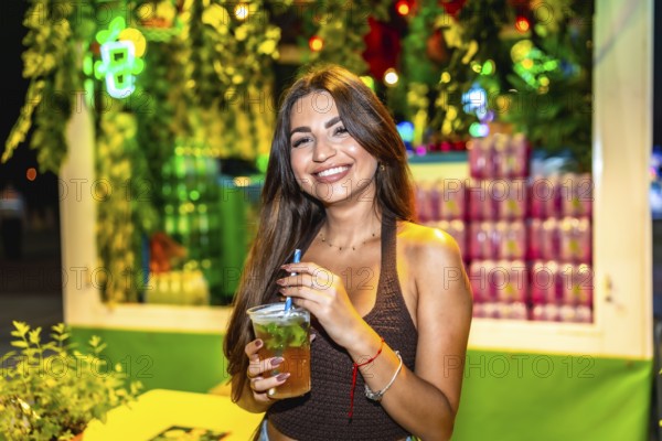 Customer savoring a mojito cocktail at a bustling night market, surrounded by colorful lights and greenery