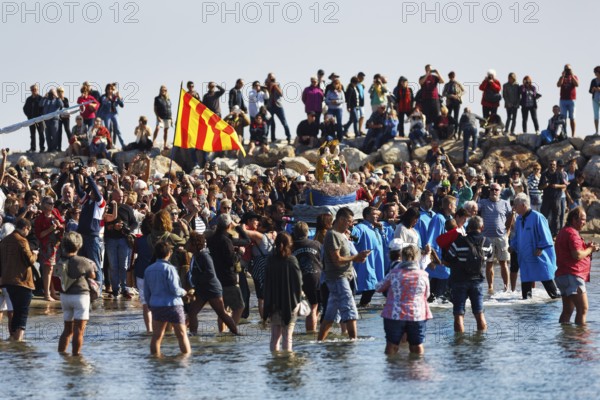 Pilgrimage, procession by the sea, pilgrims walking through water, statue of the Virgin Mary, crowd, Saintes-Maries-de-la-Mer, Camargue, France