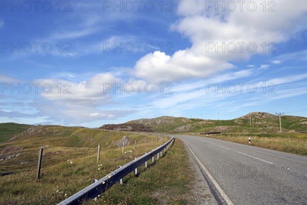 Empty road winds through hilly landscape under blue sky with clouds, Eshaness, Shetland Islands, Scotland, United Kingdom