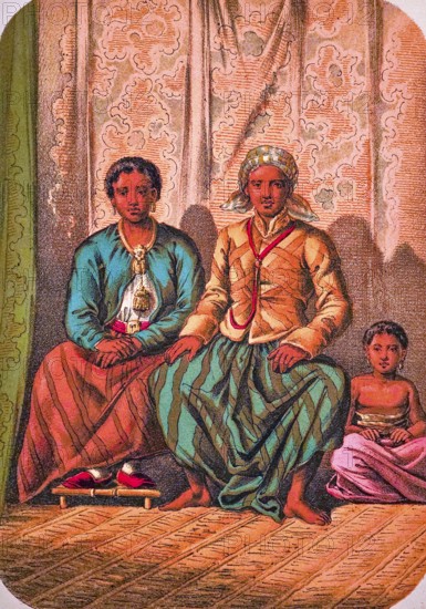 Seated Javanese family with father, mother and child, traditional clothing, headscarf, jacket, long skirt, shoes, barefoot, earrings, necklace, belt, interior with raffia rug, coloured drawing, Java, historical illustration 1877