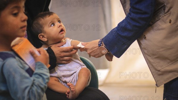 A doctor examines children's malnutrition inside a refugee camp